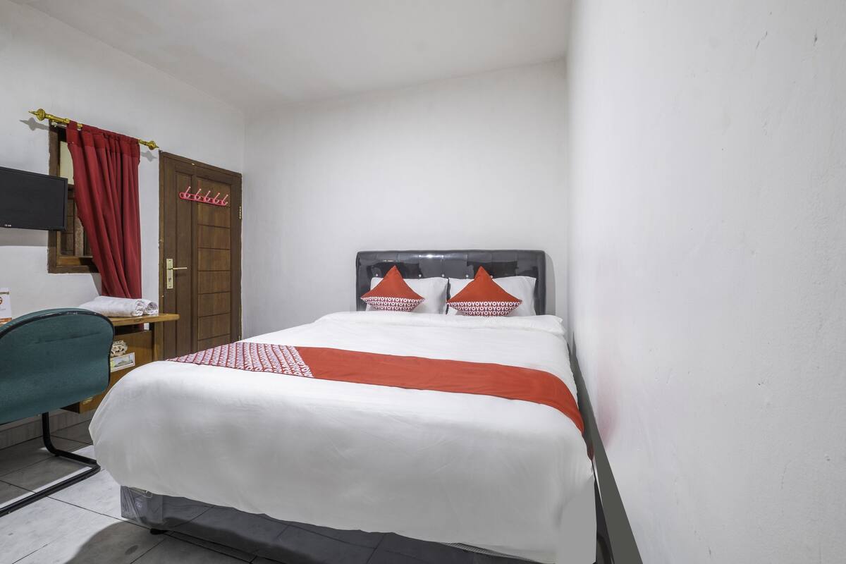 Een hotelkamer met een bed, een bureau, een stoel, een kledingkast en een televisie.