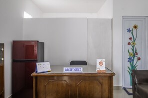 Ein Empfangstresen mit einem Schild mit der Aufschrift 'RECEPTIONIST', einem Kalender und einem Kühlschrank.