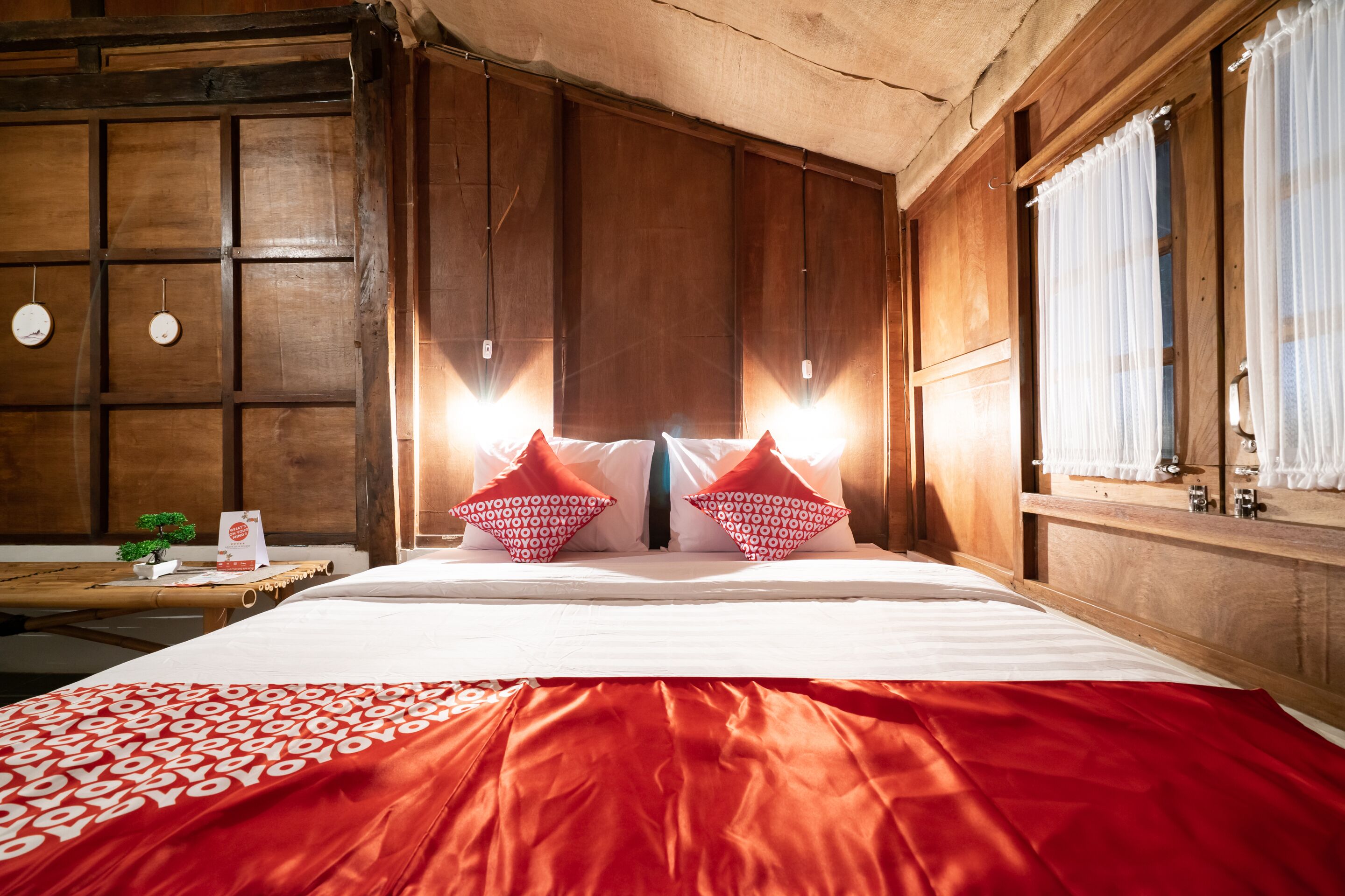 A hotel room with a large bed, wooden paneling, and a window with curtains.