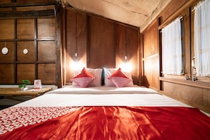 A hotel room with a large bed, wooden paneling, and a window with curtains.