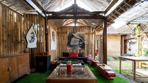 A cozy room with a wooden ceiling, a sofa, a glass coffee table, and a mural on the wall. - Hotel O Putroyono Homestay (Borobudur)