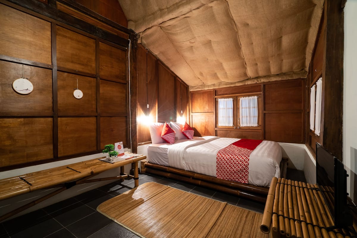 A traditional wooden room with a bed, a desk, and a window.