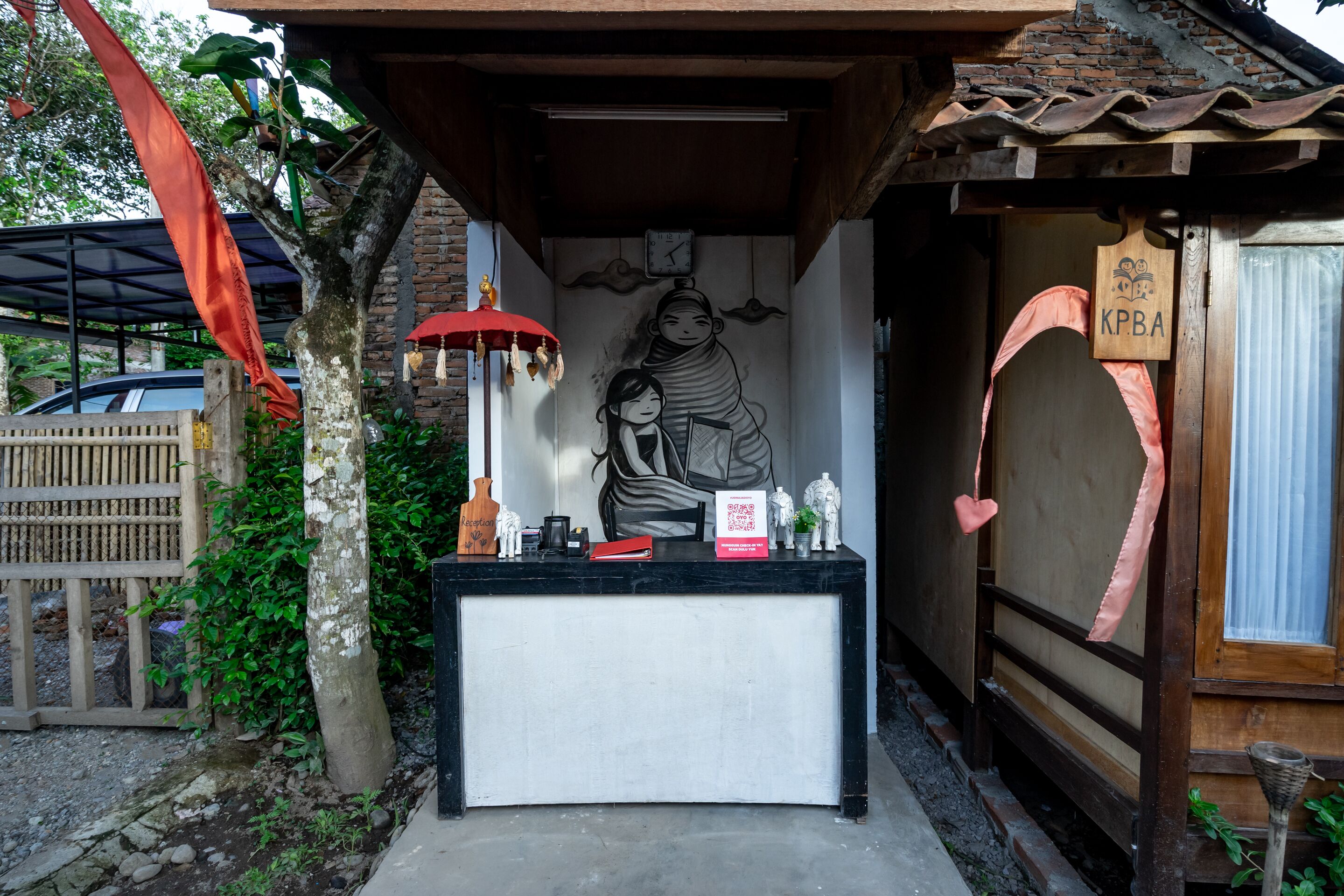 A reception desk with a mural, a clock, and a wooden sign with "KPBA" on it.