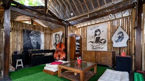 A cozy room with a wooden interior, a glass coffee table, a white sofa, and a red cushion. - Hotel O Putroyono Homestay (Borobudur)