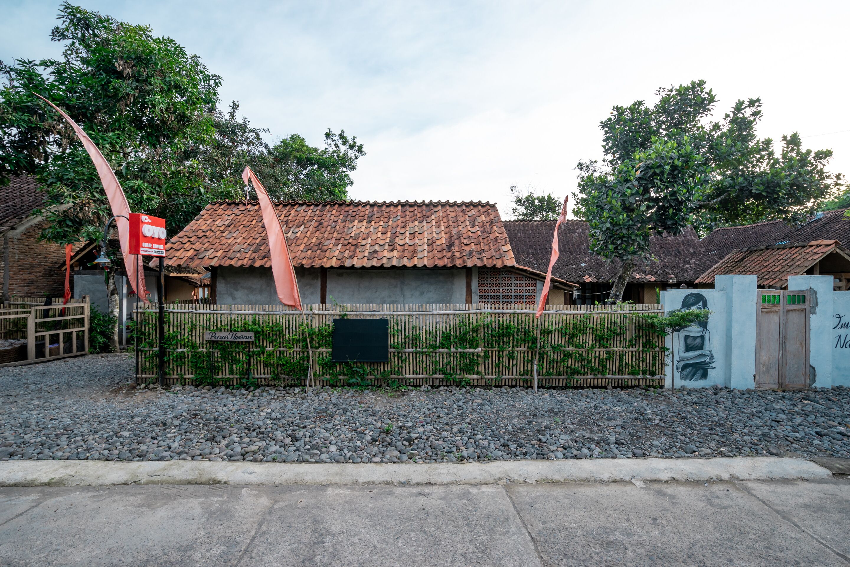 A traditional building with a tiled roof, surrounded by a bamboo fence, and a gravel pathway leading to the entrance.