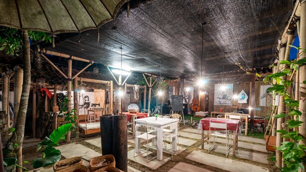 An outdoor dining area with tables and chairs, surrounded by plants and a rustic wooden structure. - Hotel O Putroyono Homestay (Borobudur)