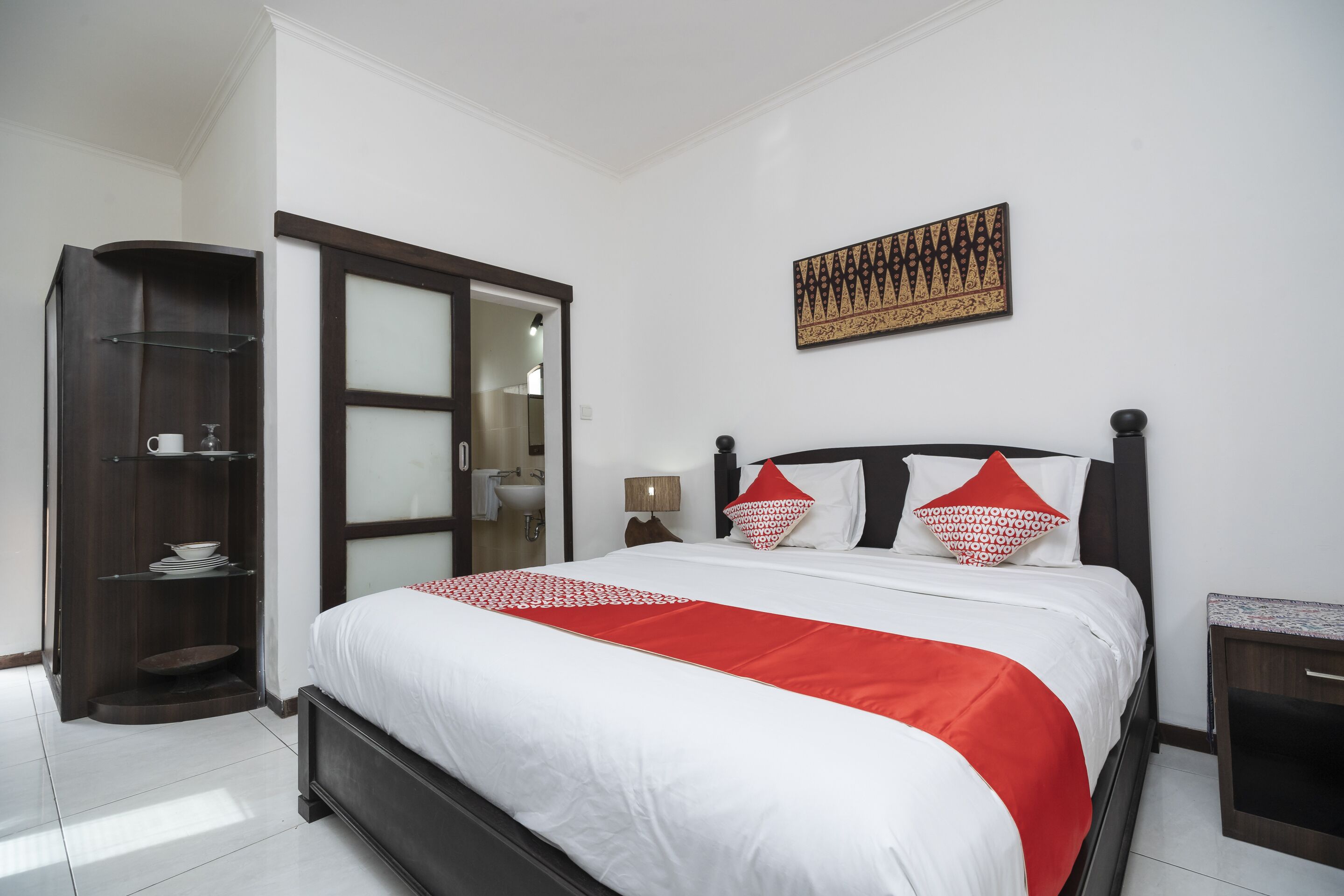 A hotel room with a bed, a wardrobe, a bathroom, and a wall-mounted artwork.