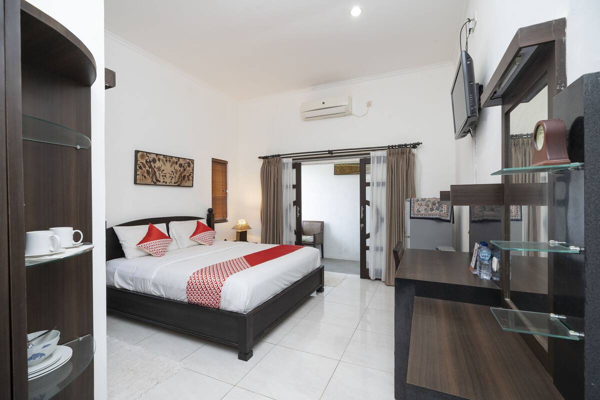 A modern hotel room with a bed, a TV, a desk, and a wardrobe.