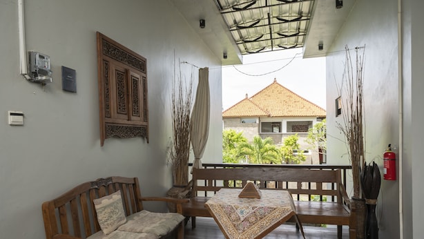 A wooden bench and table set on a balcony with a view of a house. - Hotel O Panen House (Denpasar)