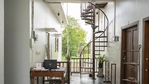 A modern interior with a spiral staircase, a wooden desk with a computer, and a potted plant. - Hotel O Panen House (Denpasar)