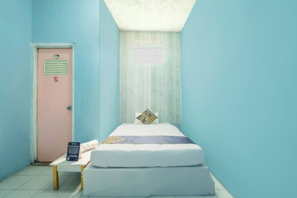 A small, neatly arranged room with a bed, a table, and a door.