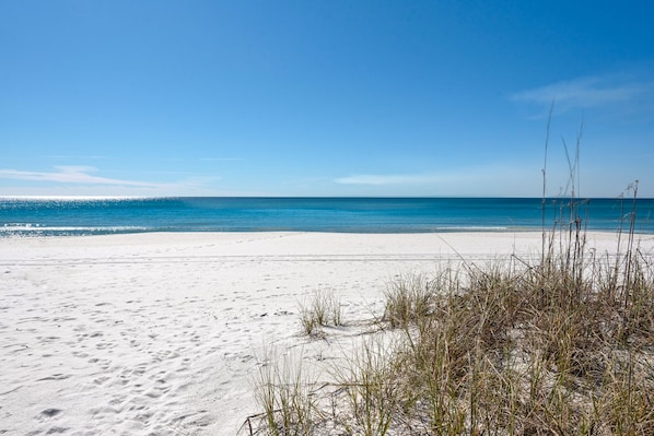 A beach with white sand and clear blue water.