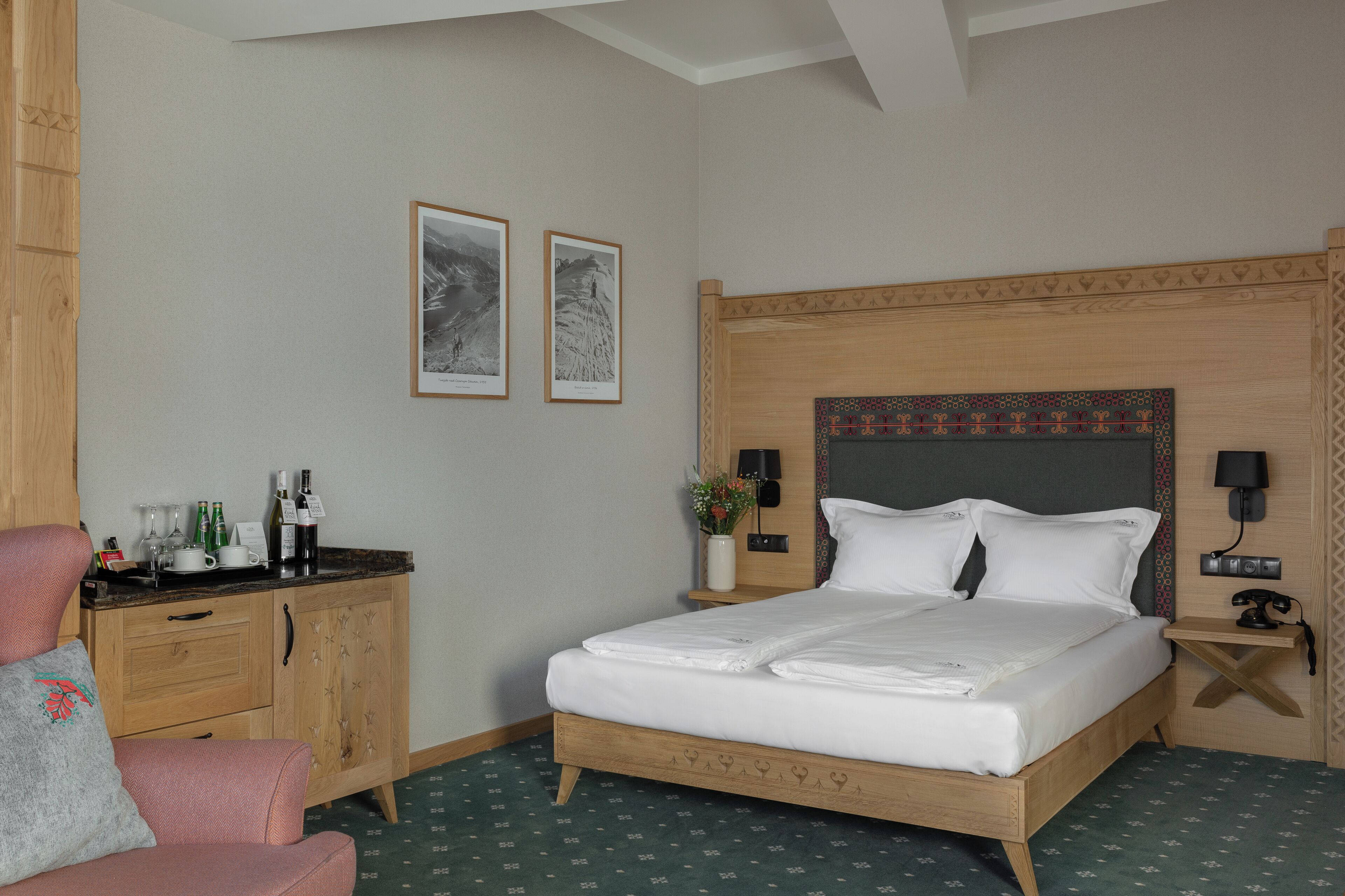 Ein Hotelzimmer mit einem hölzernen Bett, einem Nachttisch mit Lampe, einem Holzschrank und zwei gerahmten Bildern an der Wand.