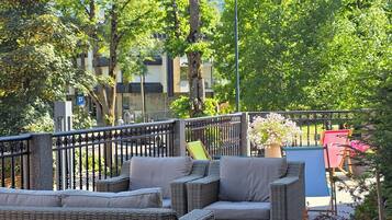Outdoor wicker furniture, a metal fence, and a view of buildings in the background.