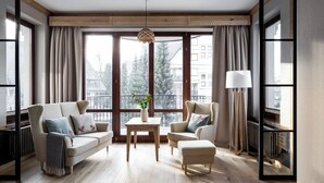 A modern living room with a sofa, armchair, ottoman, and a small table with a vase. - Aparthotel Cristina (Zakopane)