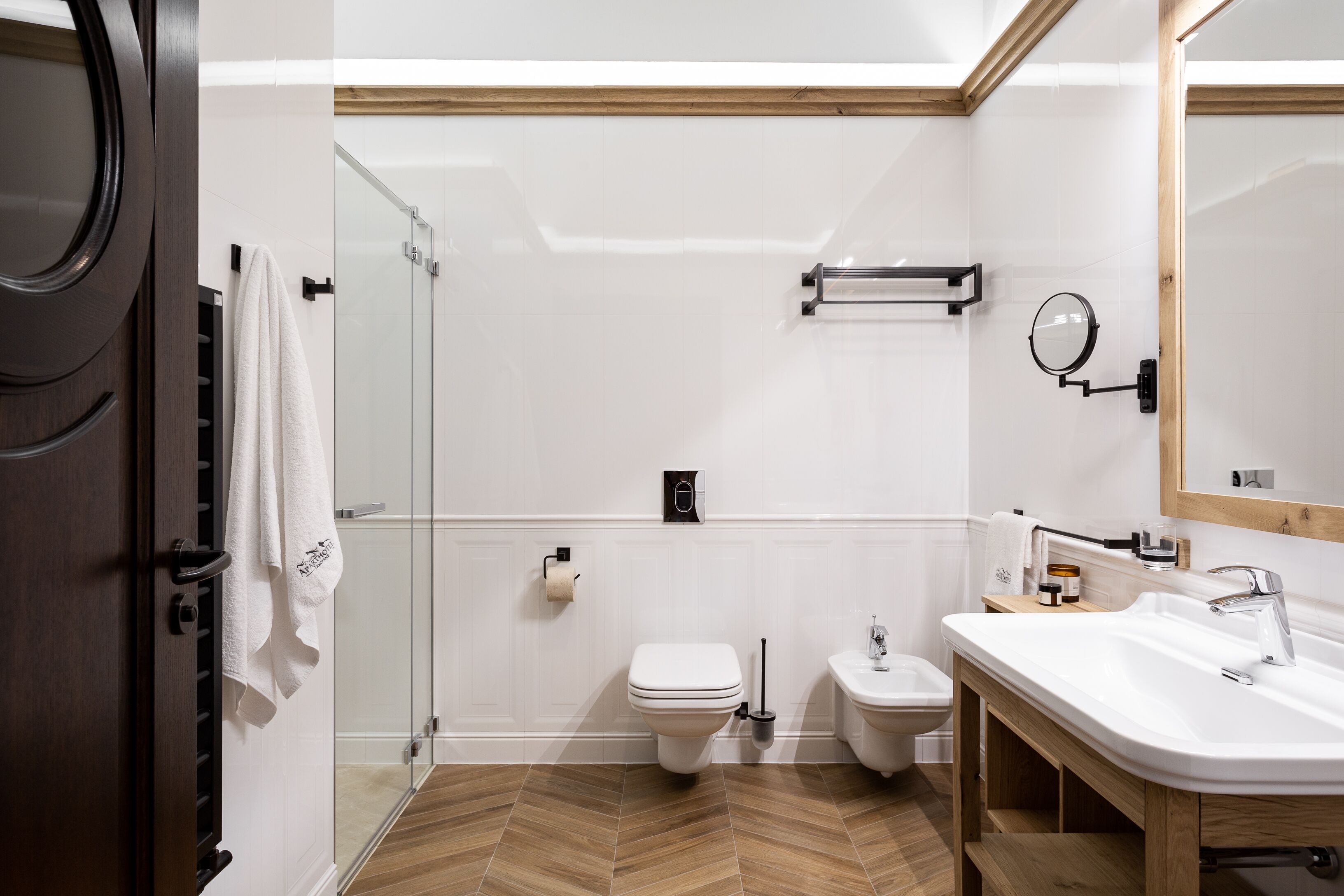 A modern bathroom with a glass shower enclosure, a toilet, a bidet, and a sink with a mirror.