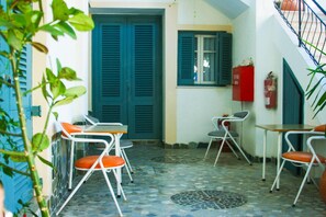 A tiled patio area with outdoor seating, a door, and a window. - George Apartments (Tilos)