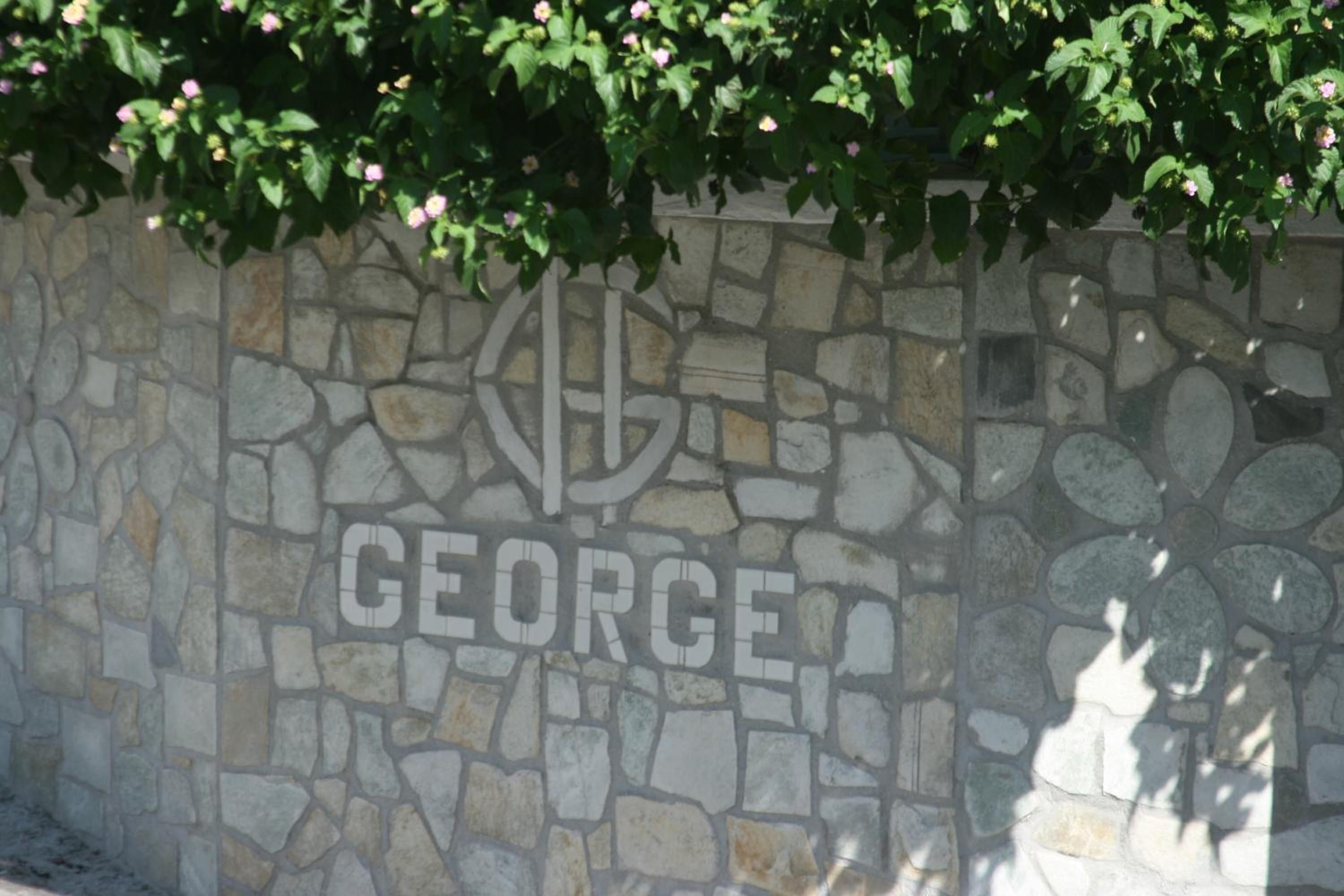 A stone wall with a logo and the name 'GEORGE' etched into it.