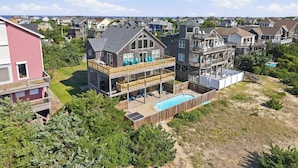 A multi-story house with a large deck, a swimming pool, and a view of the surrounding neighborhood. - To the Beach and Back at Salvo 5 Bedroom Home with a Private Pool, Spa and Near Beach Access! (Salvo)