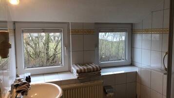 Ein Badezimmer mit Fenster, Waschbecken, Toilette und Heizkörper.