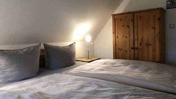Ein Schlafzimmer mit einem Bett, zwei Kissen, einem Nachttisch, einer Lampe und einem Holzschrank.
