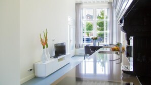 A modern kitchen with a built-in island, a flat-screen TV, and a large window with curtains. - Middelburg4you (Middelburg)
