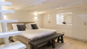 A modern bedroom with a large bed, a bench, and built-in wardrobes. - Middelburg4you (Middelburg)
