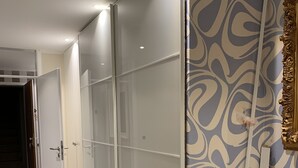 Ein Zimmer mit Schiebeglasfenster, Wand mit Muster und weißem Schreibtisch.