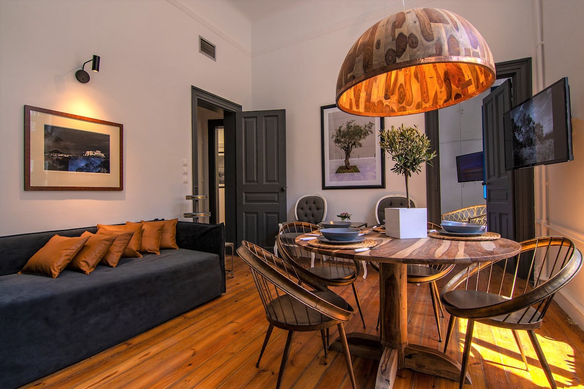 A dining area with a round wooden table, metal chairs, and a large pendant light.