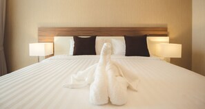 Una habitación de hotel con una cama bien hecha, dos almohadas, dos lámparas de noche y un cabecero de madera.