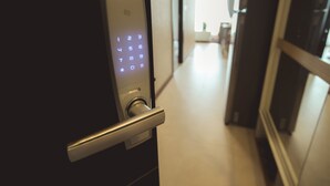 A modern door with a keypad lock and a metallic handle. - The Astra Condo (Chiang Mai)