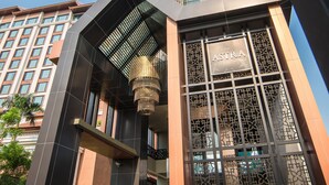 A modern building with a prominent entrance, a large chandelier, and a sign reading "The Astra." - The Astra Condo (Chiang Mai)