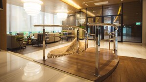 A modern lobby with a wooden floor, a central staircase, and a seating area with sofas and chairs. - The Astra Condo (Chiang Mai)