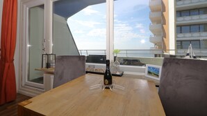 Una habitación con una mesa de madera, dos sillas, una botella de champán y vistas a un edificio con balcones.