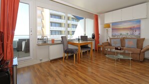 Una sala de estar moderna con piso de madera, una mesa de comedor de vidrio, un sofá y un cuadro en la pared.