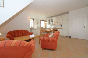 Eine moderne Küche mit weißen Schränken, einem Esstisch und orangefarbenen Sofas mit Streifen.