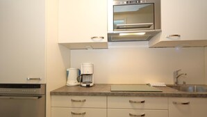 A modern kitchen with stainless steel appliances, a built-in oven, a coffee maker, and a sink.