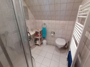 Un baño pequeño con inodoro, lavabo y zona de ducha.
