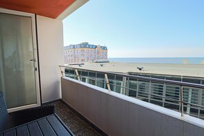 A balcony with a view of a beach and a building.