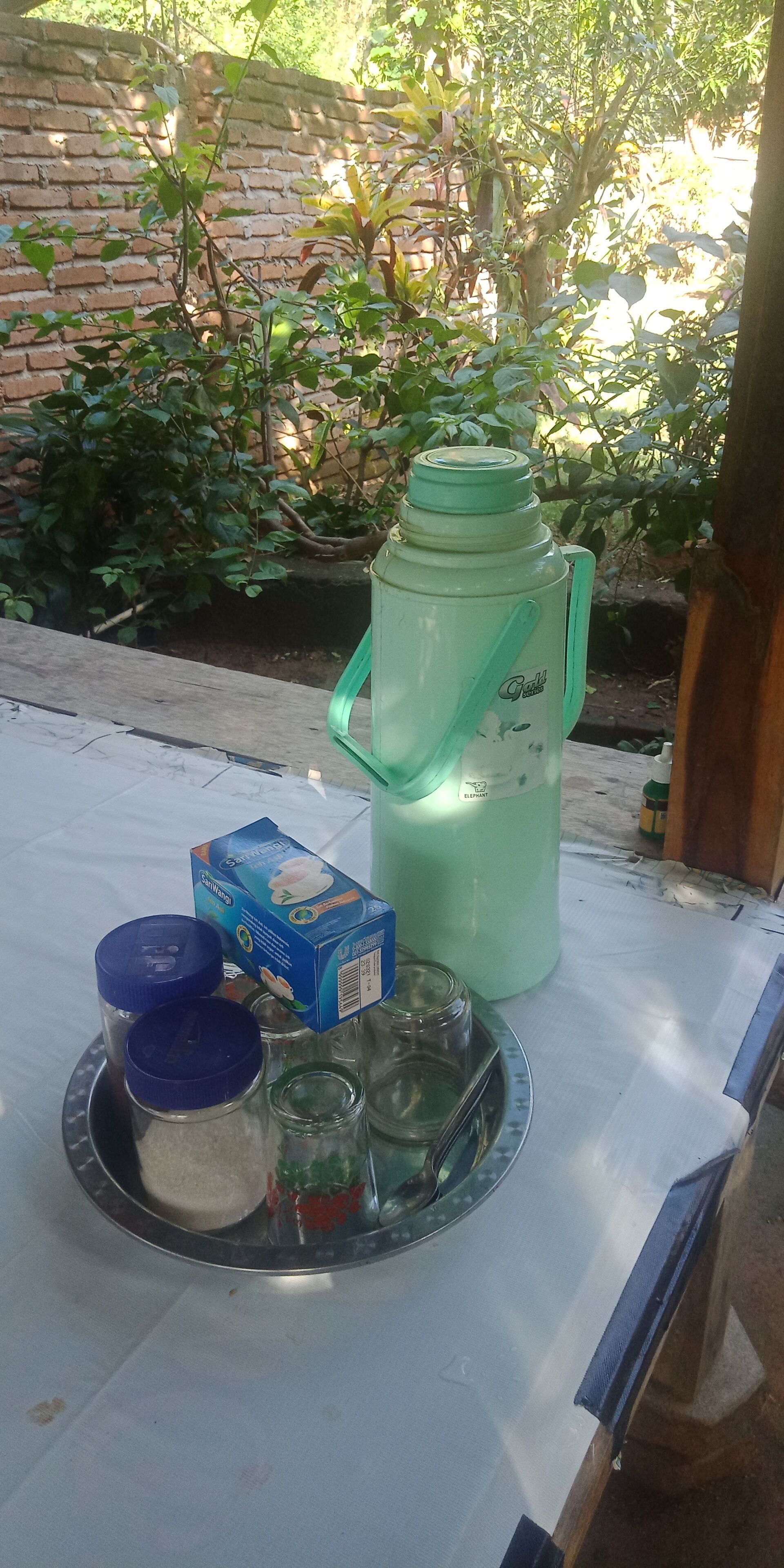 A table with a green thermos, a blue box, and jars with lids.
