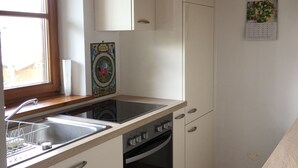 A kitchen with white cabinets, a stove, an oven, a sink, and a window.