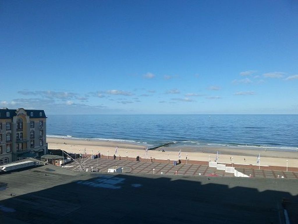 A coastal hotel with a beach view, a parking area, and a building with multiple floors.