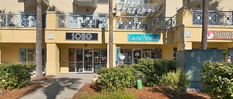 Un immeuble abritant un magasin de plage de style SOHO, Coastal Paradise, et un café appelé Sunrise Coffee.