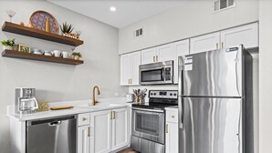 A modern kitchen with stainless steel appliances, white cabinetry, and wooden flooring. - Modern Updates, 1 Minute to the Beach!  + Free Attraction Tickets! (Santa Rosa Beach)