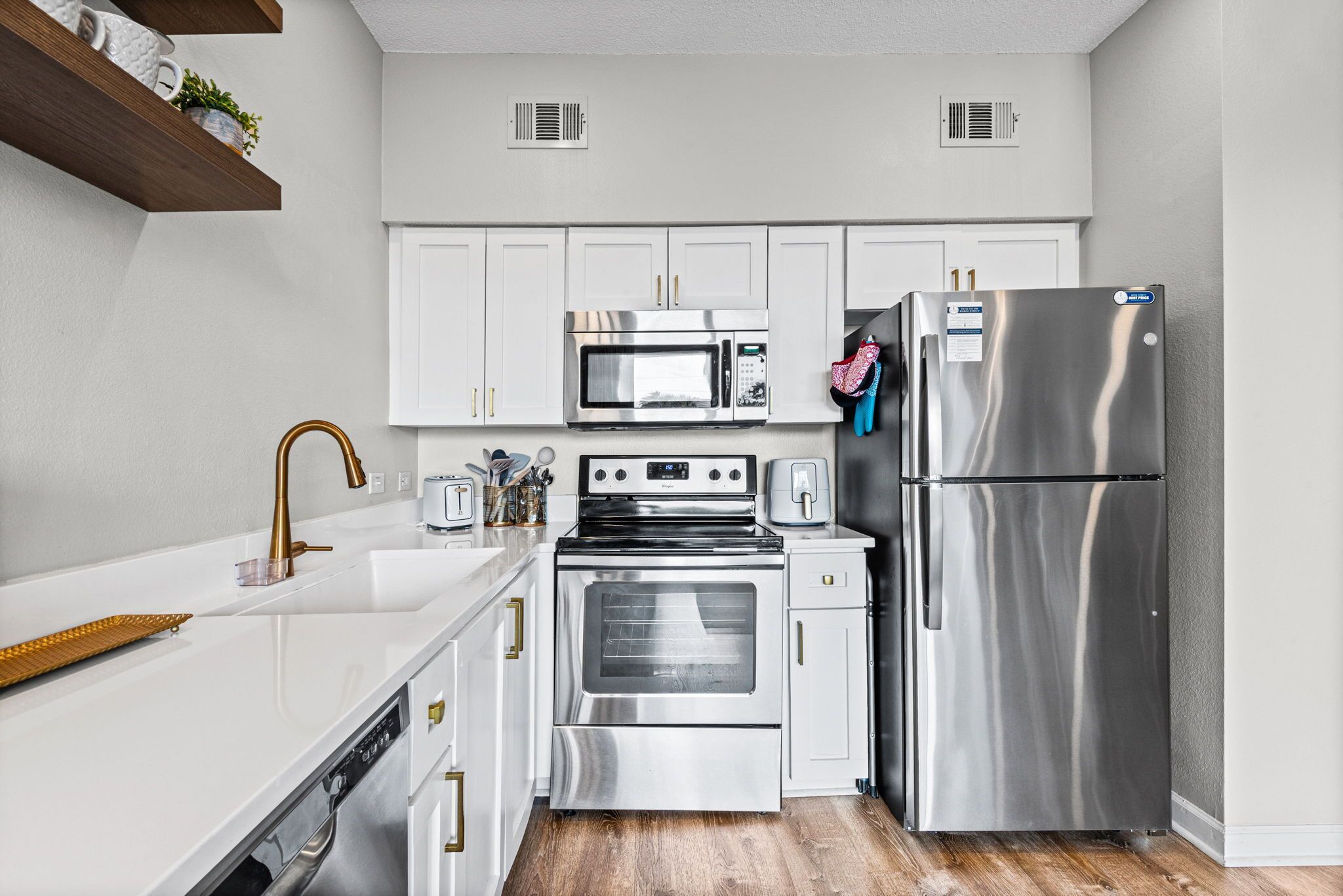 A modern kitchen with white cabinets, stainless steel appliances, and a wooden countertop.