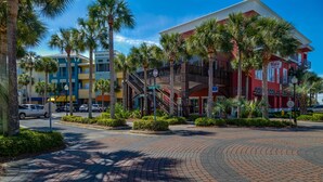 A multi-story hotel with a red facade, a balcony, and palm trees in the foreground. - Modern Updates, 1 Minute to the Beach!  + Free Attraction Tickets! (Santa Rosa Beach)