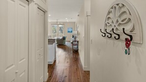 A hallway with wooden flooring, white walls, and a decorative wall piece.