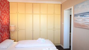 A hotel room with a bed, a wardrobe, a painting, and a lamp. - Hussmann, Germany (Sylt)