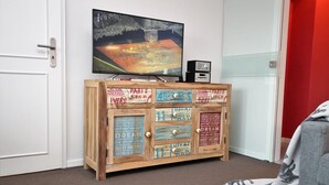 A room with a television on a wooden cabinet, a door, and a red wall. - Hussmann, Germany (Sylt)