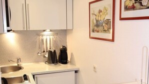 A compact kitchenette with a sink, a coffee maker, and a small refrigerator. - Hussmann, Germany (Sylt)